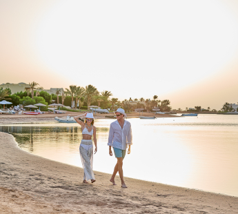 Couple walking down the beach at sunset.