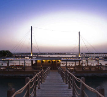 The view for wine boat with a wooden bridge over Red Sea lagoons during the sunset at Sheraton Miramar Resort in El Gouna