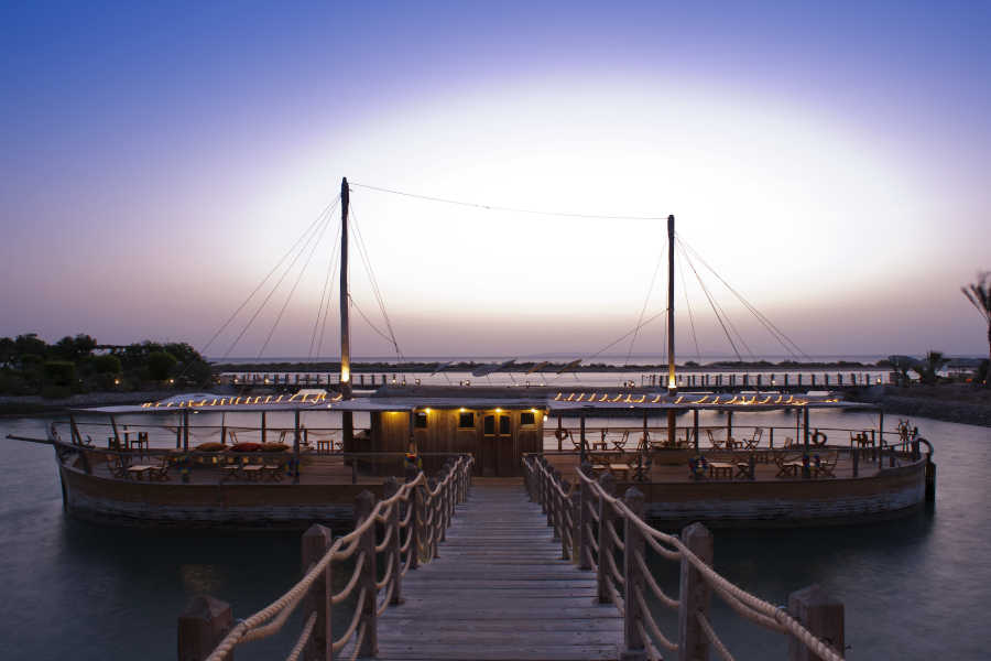 The view for wine boat with a wooden bridge over Red Sea lagoons during the sunset at Sheraton Miramar Resort in El Gouna