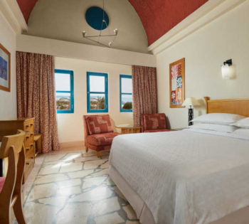 Nubian themed room of executive suite furnished with king bedding, red curtains and blue windows in Sheraton Miramar El Gouna