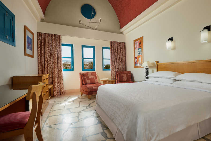 Nubian themed room of executive suite furnished with king bedding, red curtains and blue windows in Sheraton Miramar El Gouna