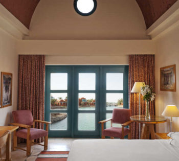 The classic room with a king bedding, 2 chairs and a wide door with lagoon view in Sheraton Miramar 5 Stars Hotel El Gouna