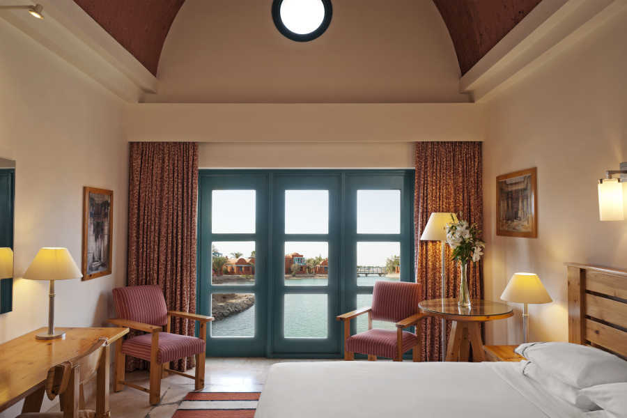 The classic room with a king bedding, 2 chairs and a wide door with lagoon view in Sheraton Miramar 5 Stars Hotel El Gouna