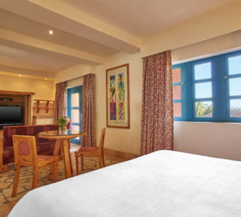 The junior suite of Sheraton Miramar El Gouna furnished with luxury king bedding and living area with dinning table and sofa