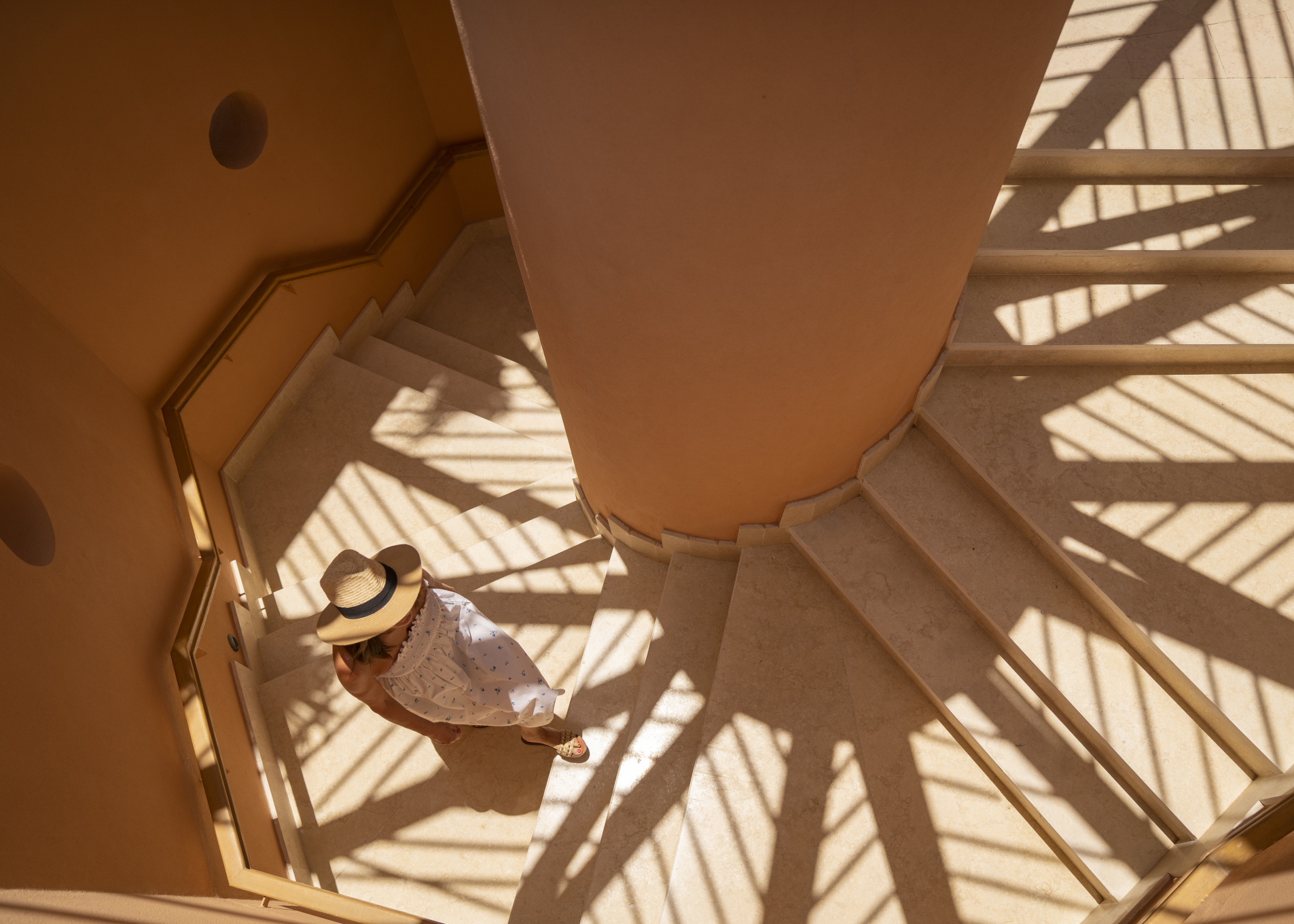 w woman wearing a dress and a hat going up the staircase in steigenberger golf resort el gouna