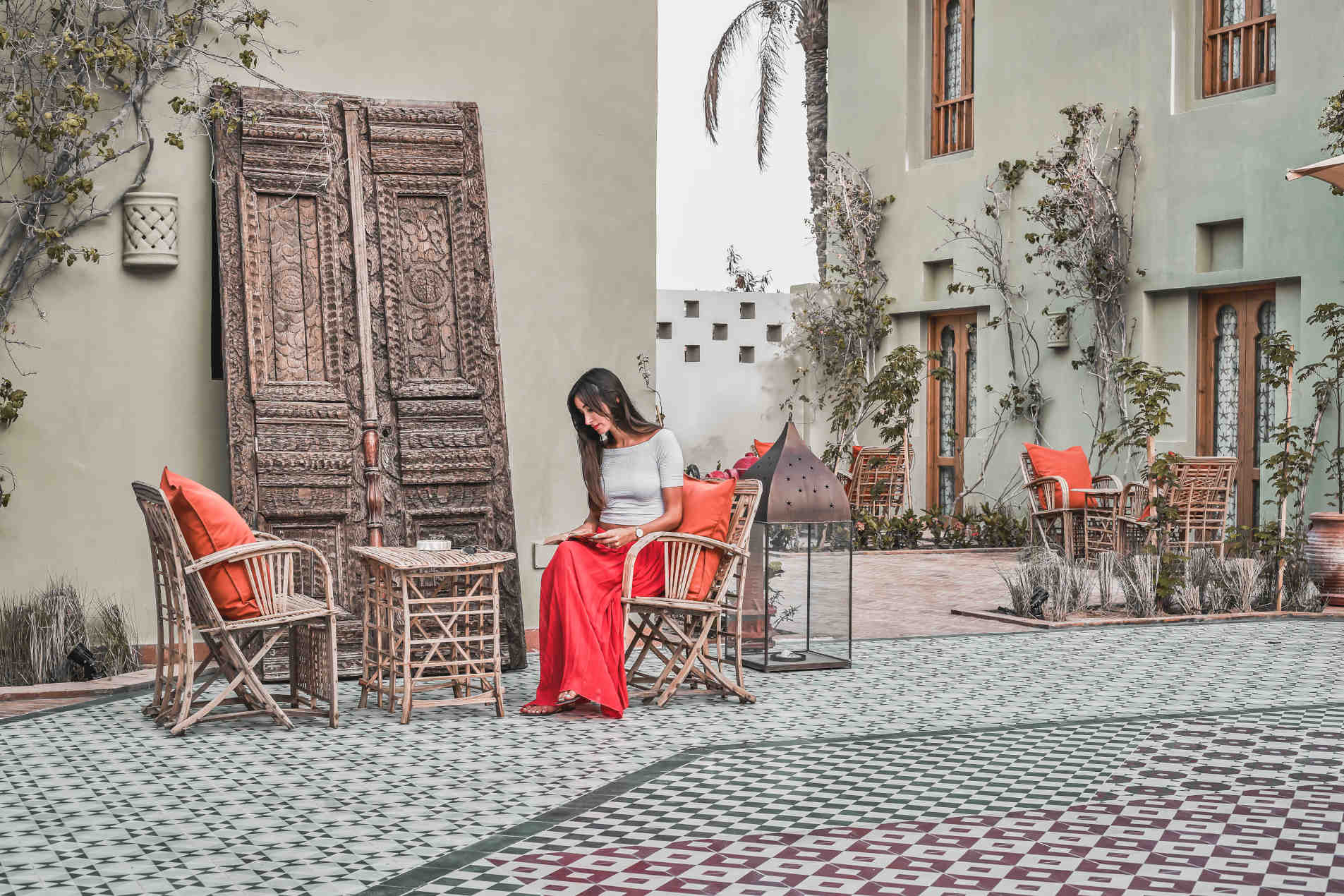 Picturesque Courtyard of Ali Pasha hotel where a female guest is sitting and reading, all reflecting the unmatched lifestyle of Ali Pasha hotel El Gouna