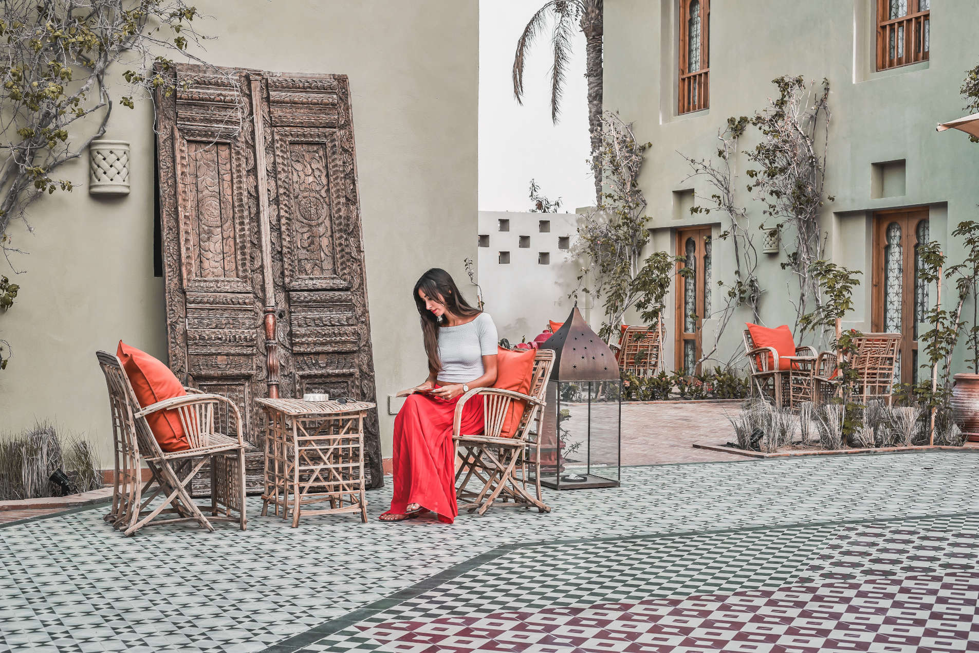 Picturesque Courtyard of Ali Pasha hotel where a female guest is sitting and reading, all reflecting the unmatched lifestyle of Ali Pasha hotel El Gouna
