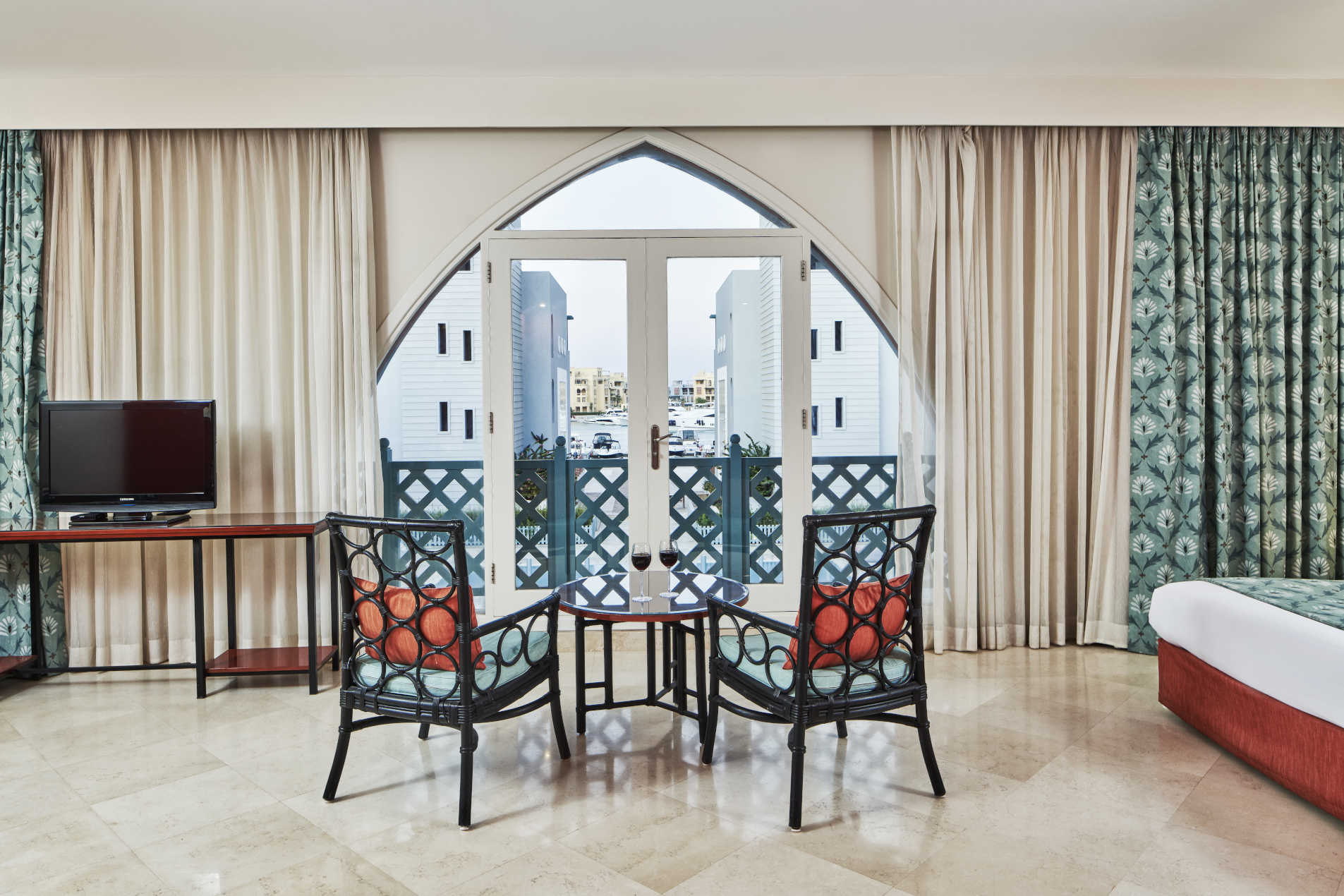 2 chairs and small table with 2 glasses of wine in front of a window that overlooking El Gouna Marina at Fanadir Hotel