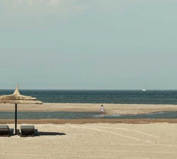 The sandy beach of Casa Cook Resort in El Gouna Red Sea with laid-back sunbeds and umbrellas and the view of blue crystal water