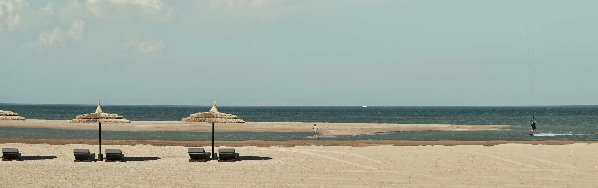 The sandy beach of Casa Cook Resort in El Gouna Red Sea with laid-back sunbeds and umbrellas and the view of blue crystal water