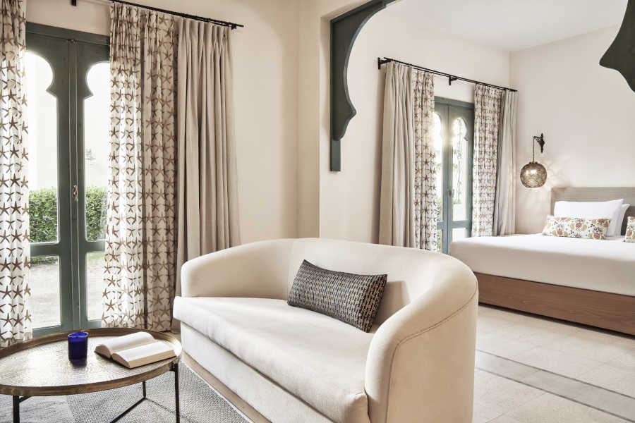 king bedroom & living area of Ali Pasha Hotel suite both modernly furnished with two patio doors with garden outside