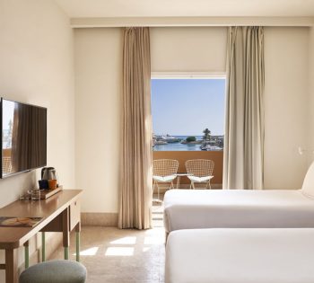 Captain's Inn Marina View Room with two twin beds, flat screen TV, dressing table and a seating area in the room terrace