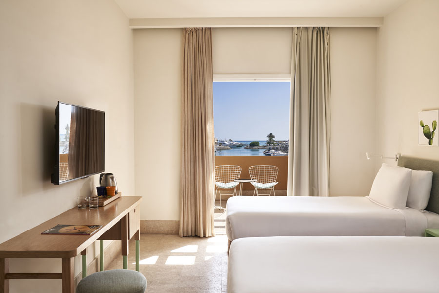 Captain's Inn Marina View Room with two twin beds, flat screen TV, dressing table and a seating area in the room terrace