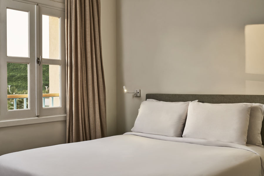 Captain's Inn Standard Room with biege walls a King size bed and a courtyard view on the pleasant greenery from the window