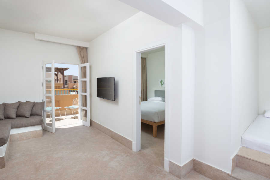 Captain's Inn Hotel El Gouna Captain Suite Modernly furnished with king bed, floor bed & a comfy sofa with flat screen TV ahead