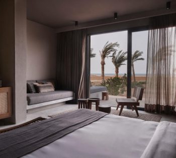 The spacious king-sized bedroom with built in sofa and a small tea table with a wide glass window connected the outdoor terrace with Red sea views in casa cook Egypt hotel