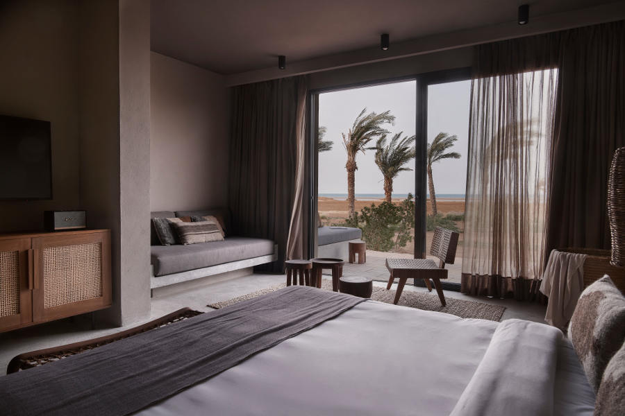 The spacious king-sized bedroom with built in sofa and a small tea table with a wide glass window connected the outdoor terrace with Red sea views in casa cook Egypt hotel
