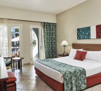 Room of Junior Suite and windows that overlooking pool with dark orange and green pattern bedding at Fanadir Hotel El Gouna