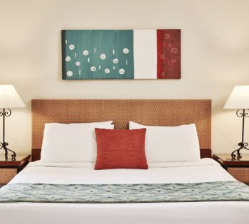 The king sized bed of Fanadir Hotel in El Gouna with 2 side tables and 2 chandeliers at the accessible room