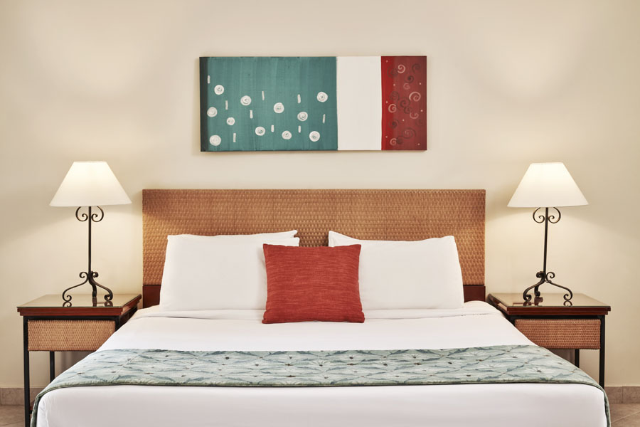 The king sized bed of Fanadir Hotel in El Gouna with 2 side tables and 2 chandeliers at the accessible room