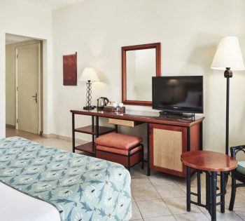 Fanadir Hotel Standard Room with a TV above a dressing table and its chair and mirror in El Gouna luxury accommodation