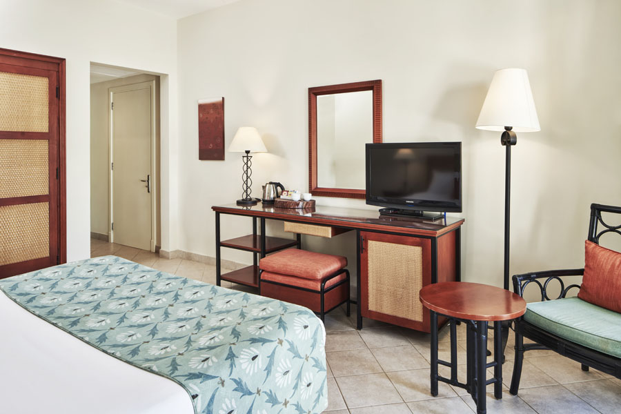 Fanadir Hotel Standard Room with a TV above a dressing table and its chair and mirror in El Gouna luxury accommodation