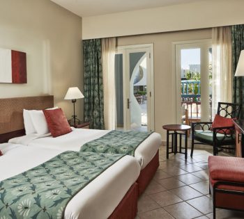 The 2 twins luxury bedding at Fanadir standard room themed with the orange present in cushions and green curtains in El Gouna