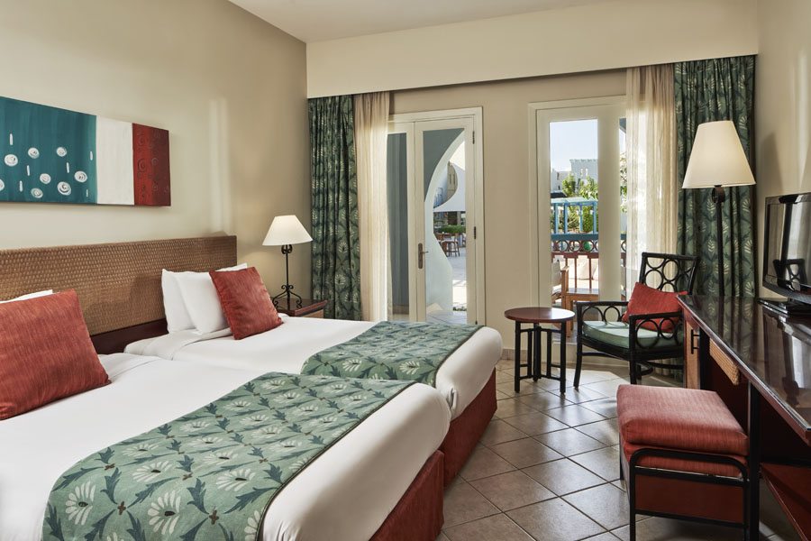 The 2 twins luxury bedding at Fanadir standard room themed with the orange present in cushions and green curtains in El Gouna