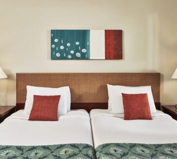 2 twins bed of Fanadir Hotel in El Gouna with 2 side tables and 2 chandelier at the accessible rooms with orange green theme