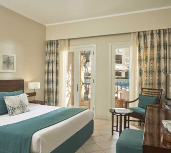 Accessible room of Mosaique hotel furnished by a king bed, a dressing table and a small table for coffee in El Gouna Hotels