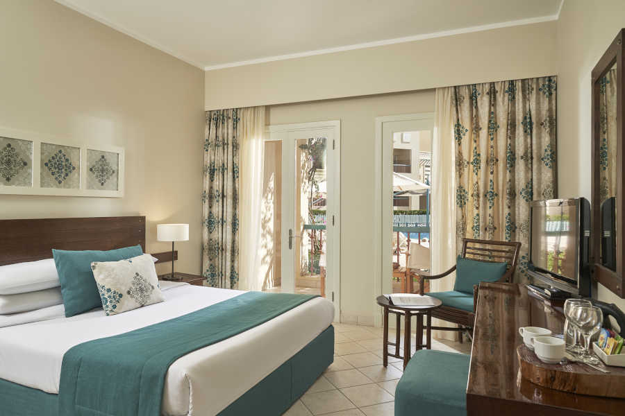 Accessible room of Mosaique hotel furnished by a king bed, a dressing table and a small table for coffee in El Gouna Hotels