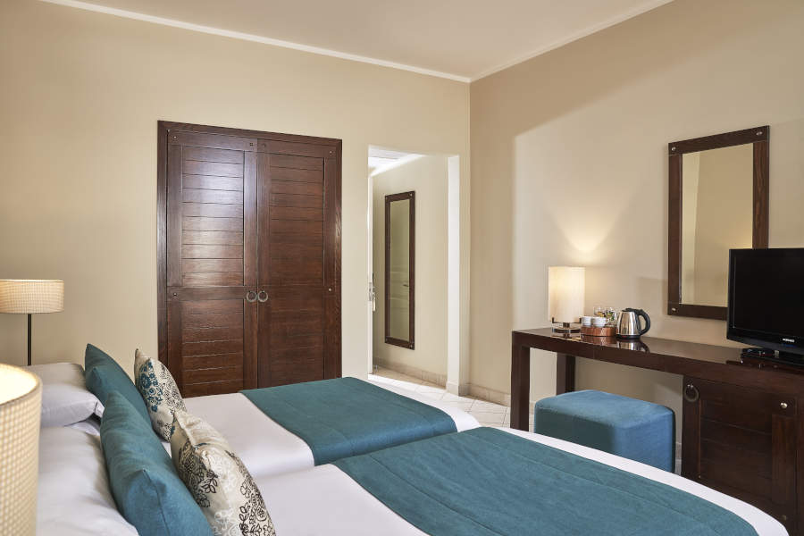 The twin luxury beddings of Mosaique Hotel with dressing table and coffee amenities and a wardrobe in El Gouna Red Sea