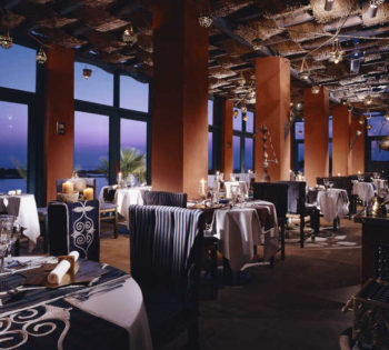 Dining tables of oriental restaurant at Sheraton Miramar El Gouna with Red Sea panoramic view from ceiling-to-floor windows