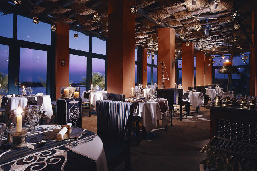 Dining tables of oriental restaurant at Sheraton Miramar El Gouna with Red Sea panoramic view from ceiling-to-floor windows