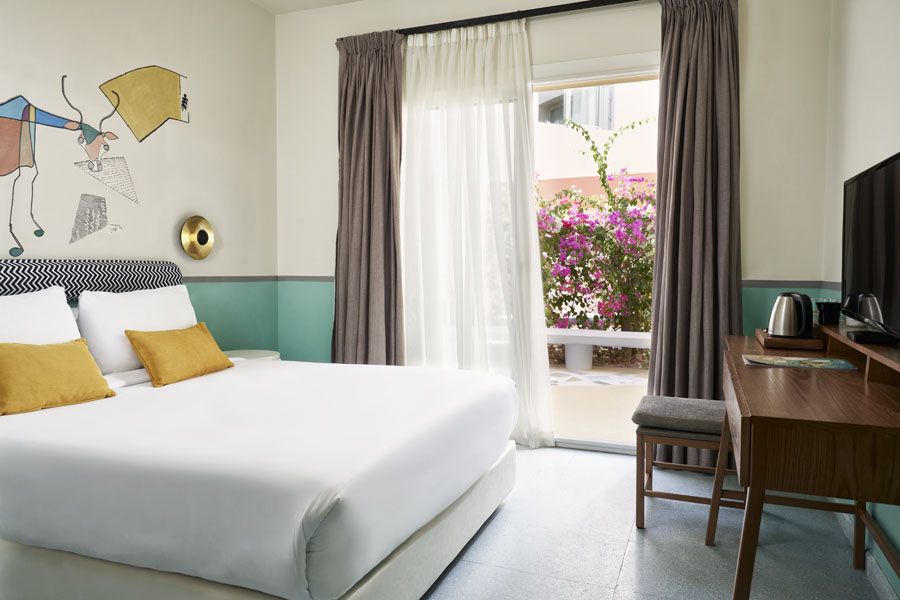 Earth Theme standard room on courtyard of Turtl'es Inn hotel El Gouna, with king size bed & cow hand-drawn art behind