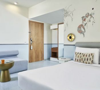 Water theme marina view room of Turtle's Inn hotel ElGouna with sofa, fish & reefs hand-drawn art on wall behind King size bed