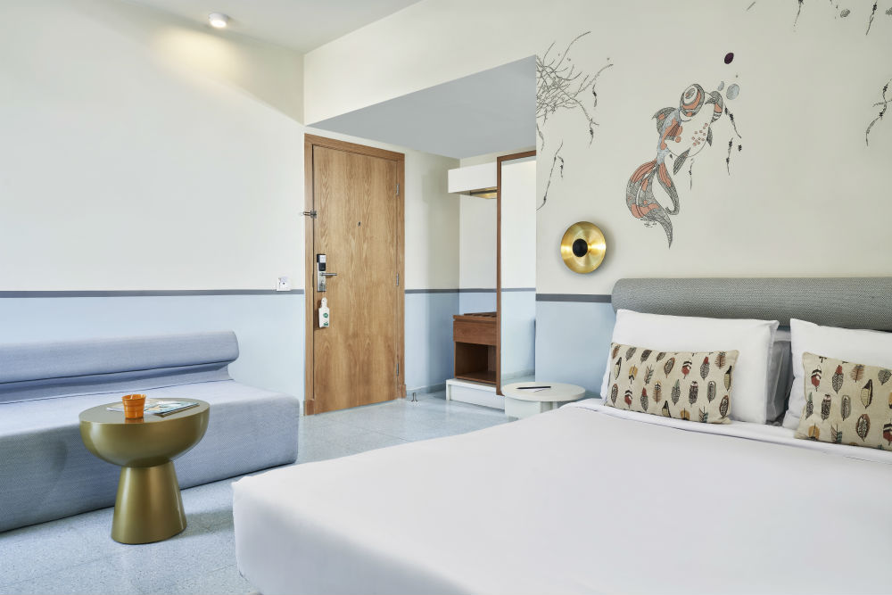 Water theme marina view room of Turtle's Inn hotel ElGouna with sofa, fish & reefs hand-drawn art on wall behind King size bed