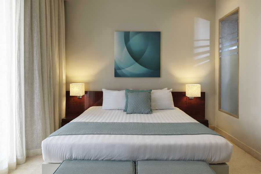 The king bedroom of Ancient Sands Apartment in El Gouna decorated with beige-blue theme and a glass window for a daylight