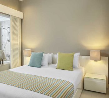 the king bed sized of junior suite with 2 sided tables and chandeliers and a door to the bathroom at Ancient Sands Resort luxury accommodation in El Gouna