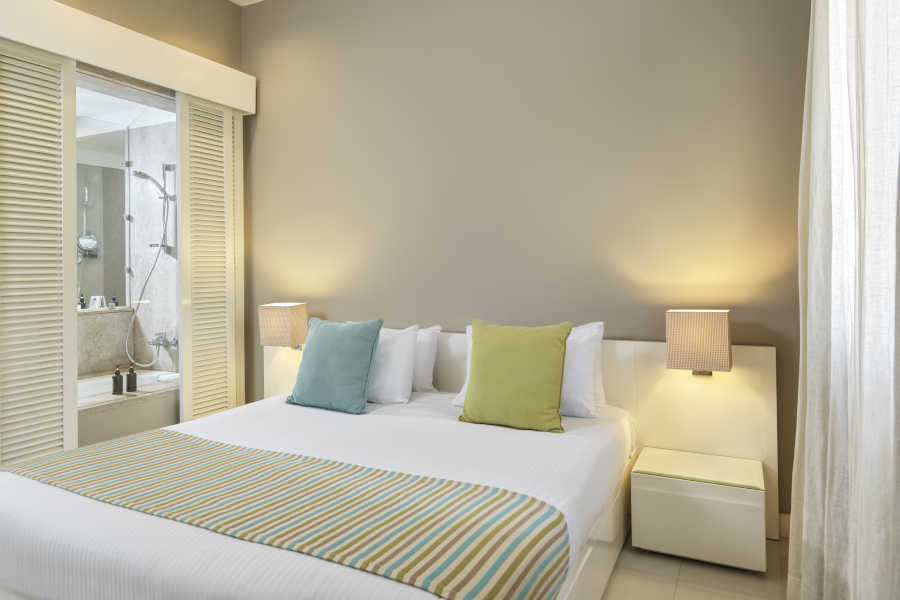 the king bed sized of junior suite with 2 sided tables and chandeliers and a door to the bathroom at Ancient Sands Resort luxury accommodation in El Gouna