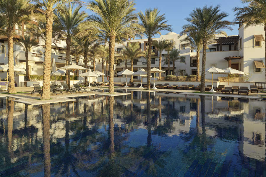 The swimming pool for adults in Ancient Sands Resort surrounded with laid-back sunbeds for spending a relaxing vacation in El Gouna