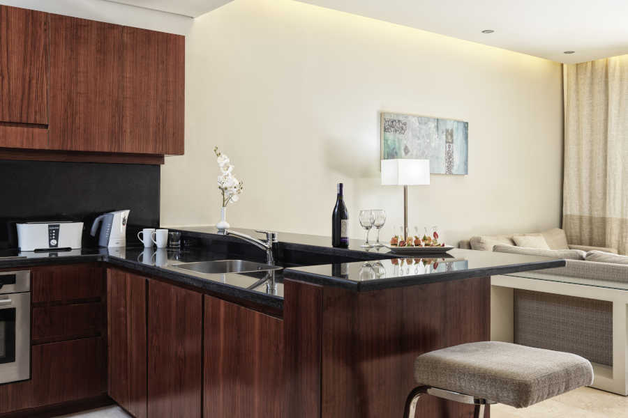 The modern kitchen of an apartment in Ancient Sands Resort and Residences in El Gouna with a bar and chairs