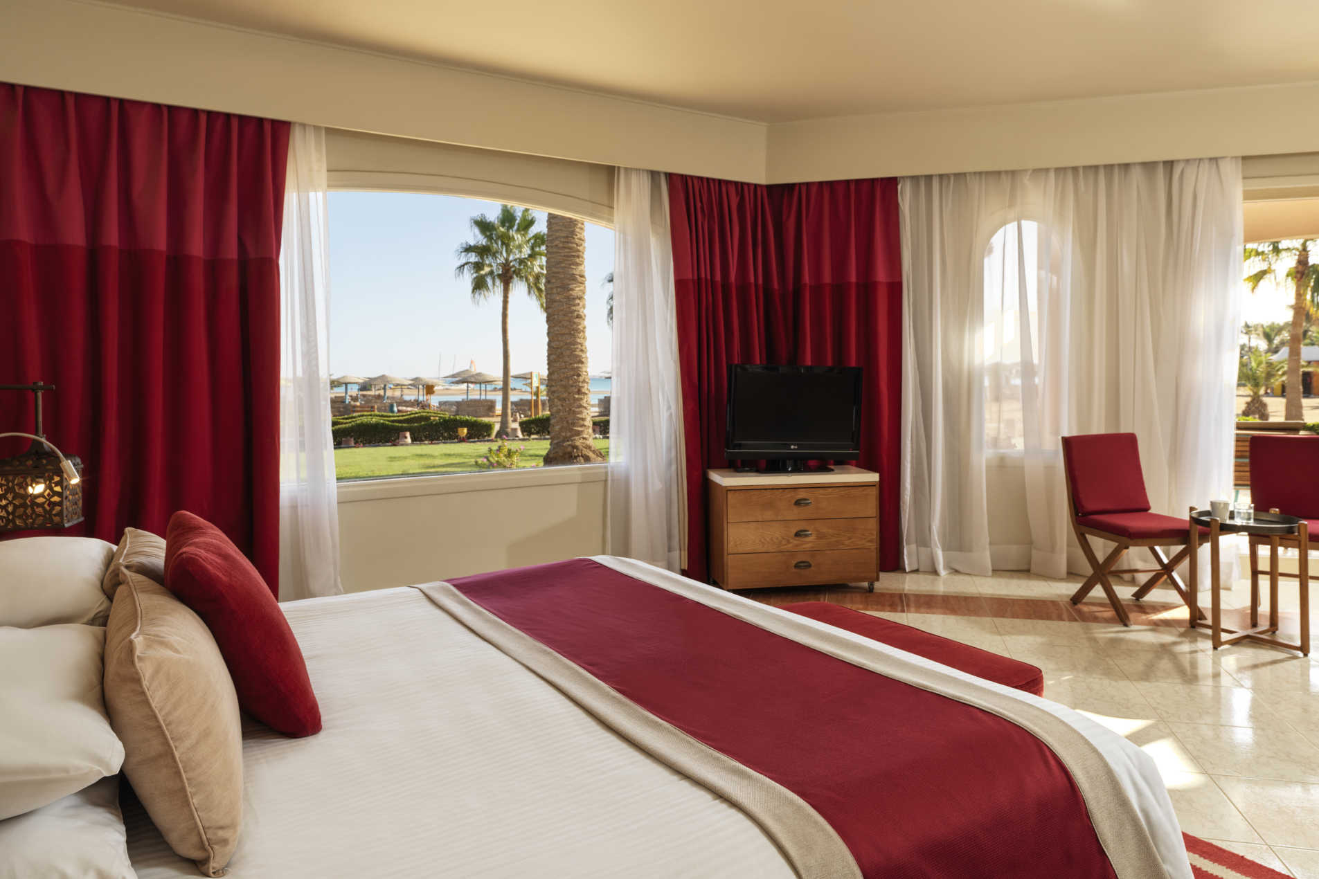 The kingbed of junior suite at Labranda Club Paradisio Hotel in El Gouna in a red theme and overlooking Red Sea waters and hotel gardens