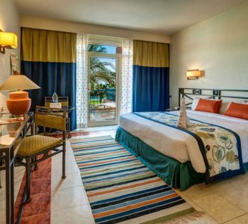 The master bedroom of Club Paradisio Hotel Suite in blue yellow theme and a wide door to the terrace with garden view