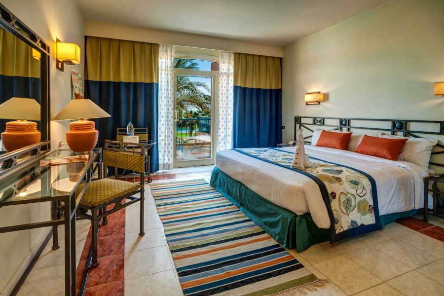 The master bedroom of Club Paradisio Hotel Suite in blue yellow theme and a wide door to the terrace with garden view