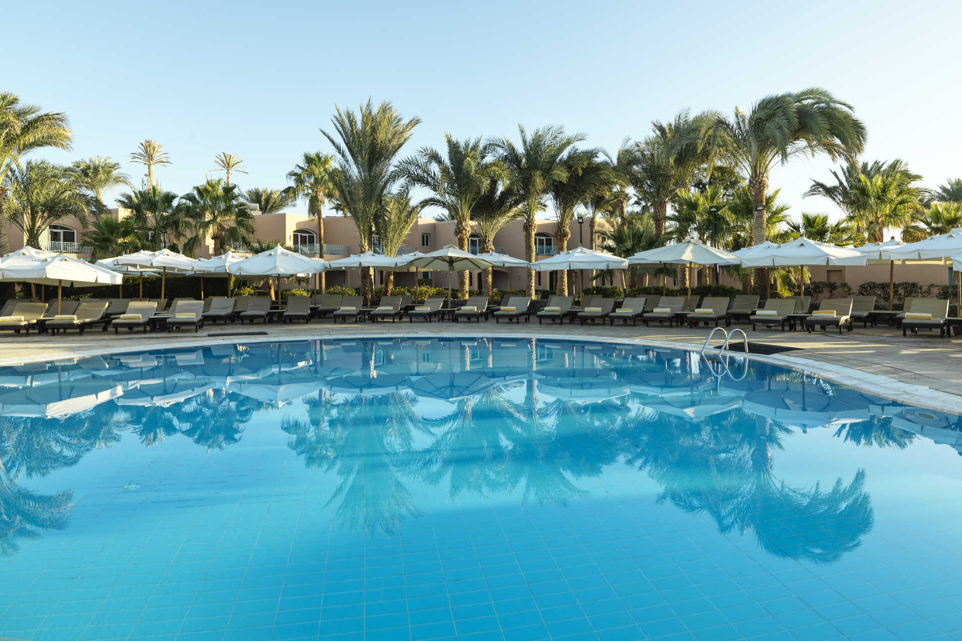 Swimming Pool of Labranda Club Paradisio Hotel in El Gouna surrounded with laid back sunbeds and umbrellas