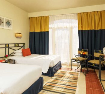 The twin beds of Labranda Club Paradisio suite with a small coffee table and 2 chairs in El Gouna Hotels