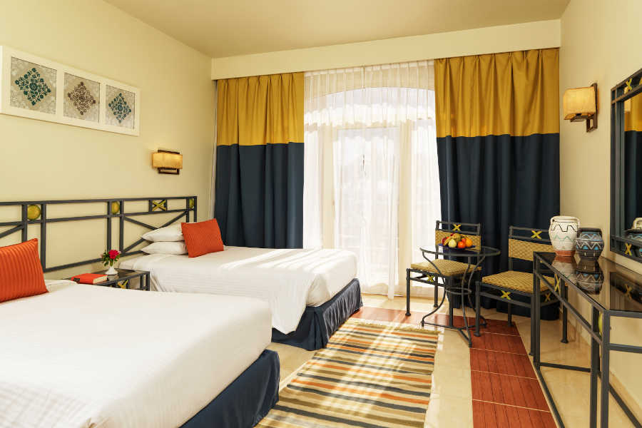 The twin beds of Labranda Club Paradisio suite with a small coffee table and 2 chairs in El Gouna Hotels