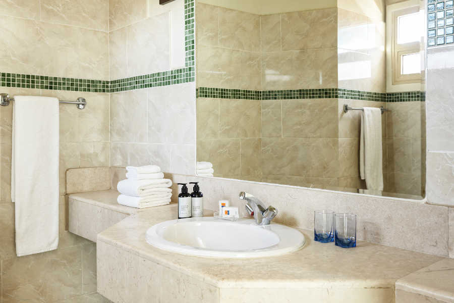 The marbled bathroom with a wide mirror, toiletries and towels
