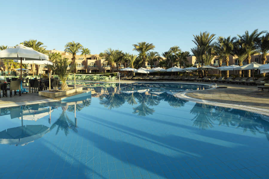 The swimming pool of Labranda Club Paradisio Hotel in El Gouna surrounded with laid back sun beds and umbrellas and a pool bar